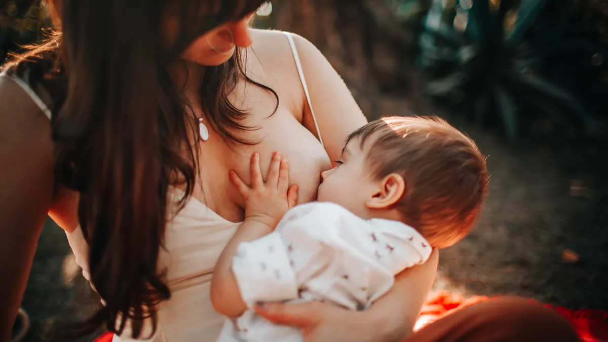 Woman breastfeeding baby while seated outdoors