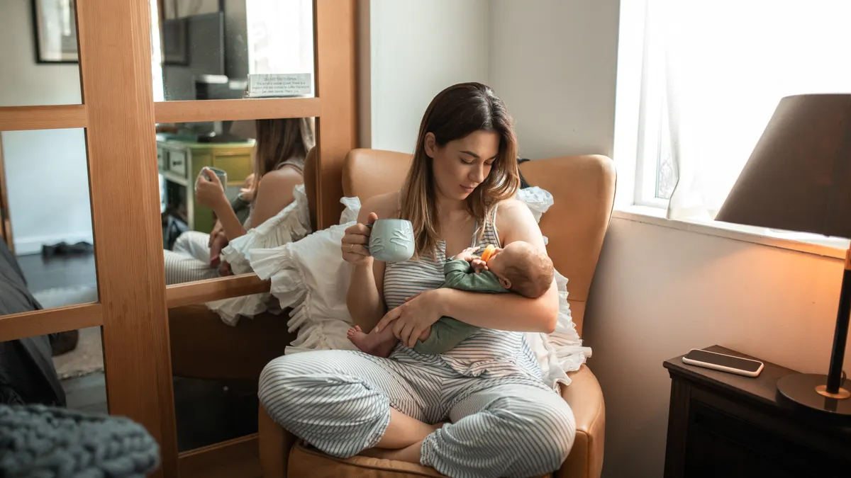Mother breastfeeding baby while seated in an armchair