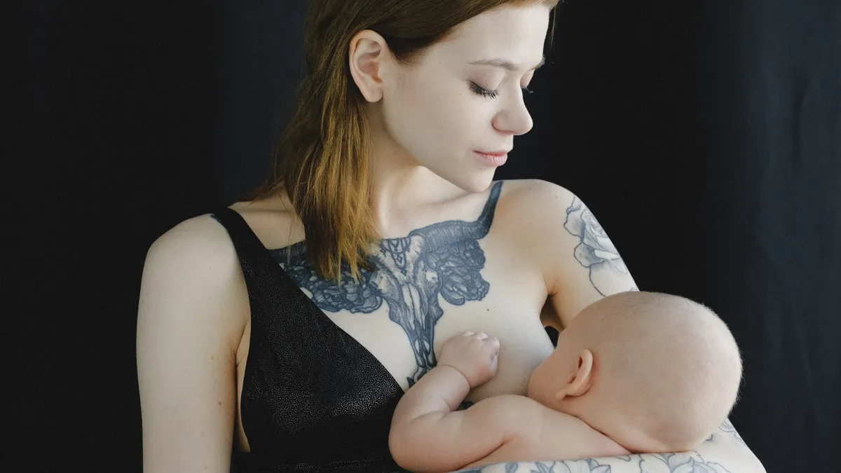 Mother breastfeeding an infant against a dark background